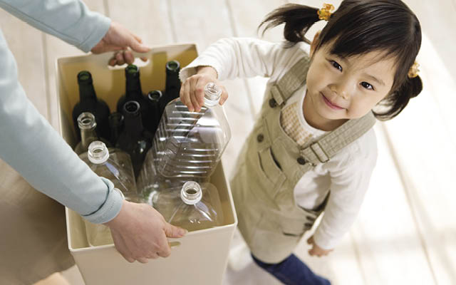 child putting recyclables in a box