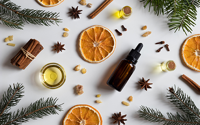 A collection of pine cones, cinnamon sticks, dried orange slices, and essential oils