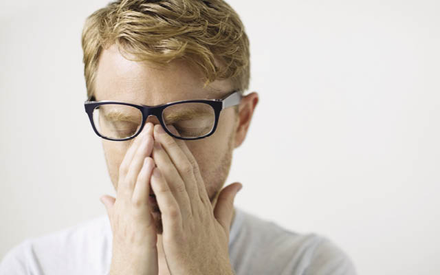 man with glasses rubbing eyes