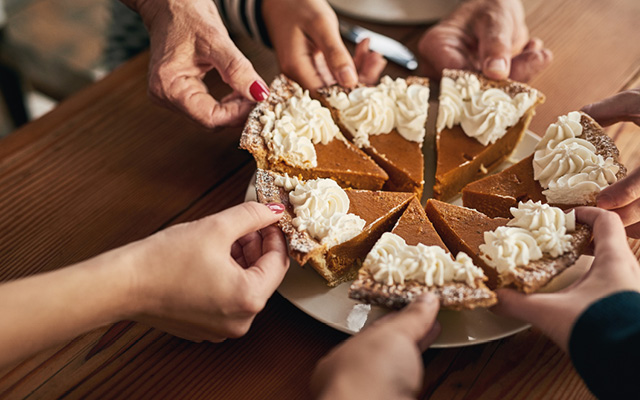 Shot of a group unrecognizable people's hands each taking a slice of cake on a dinner table