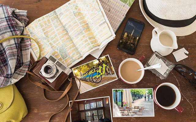 A picture of maps, a camera, and other things people might pack when planning a trip.