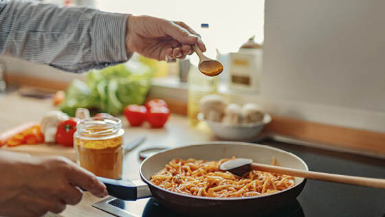 A person sprinkles turmeric on a dish.