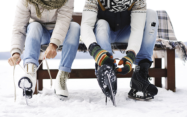 two people tying their ice skates on a bench