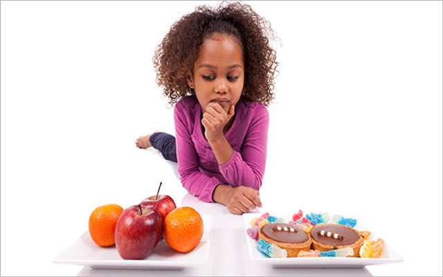 A young girl decides between apples and an unhealthy treat.