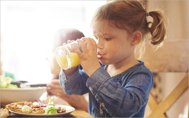A little girl drinks juice.