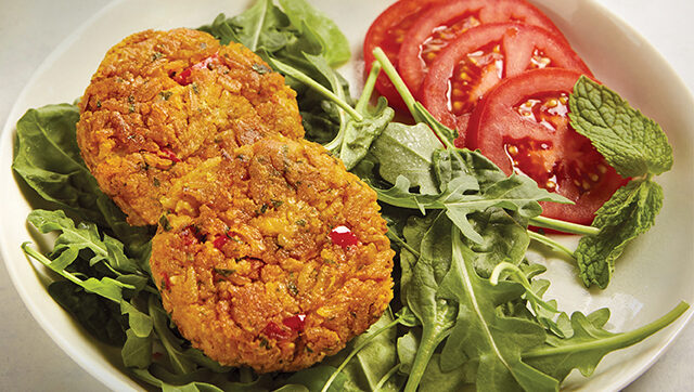 Plate of chickpea burger and tomatoes on greens