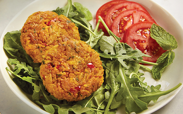 Plate of chickpea burger and tomatoes on greens