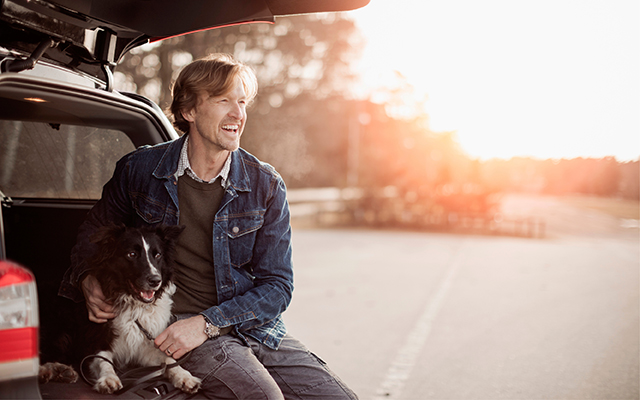 man sitting with dog on tailgate