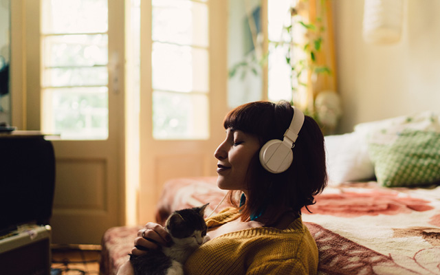 Woman listening to headphones and holding kitten