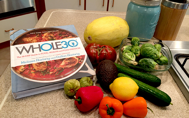 Whole30 cookbook alongside several fresh veggies