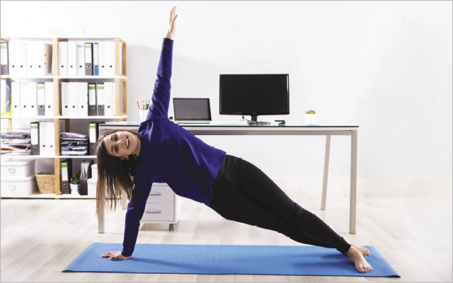 A woman demonstrates how to do workday workouts near her desk.
