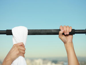 bar with one hand holding a towel looped over the bar with the other in an overhand postion