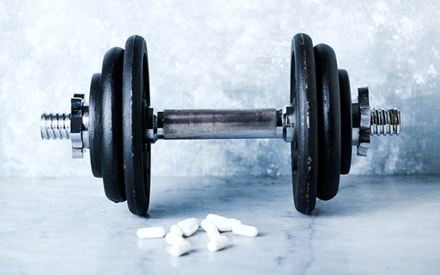 A picture of a barbell and several pills
