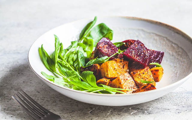 Baked beets and sweet potato salad with spinach.
