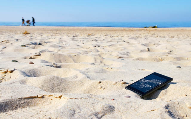 A broken cellphone sits on the beach.