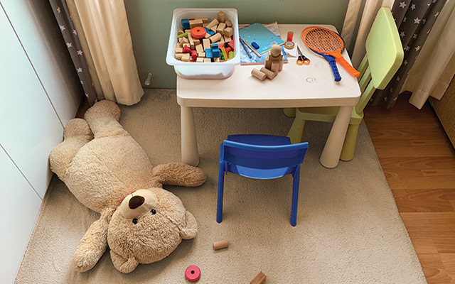 A messy kid's playroom with a teddy bear on the floor