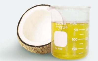 A fresh coconut and a glass beaker full of oil are pictured.