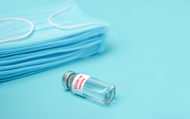 A vial of immunizations next to some blue hospital gowns