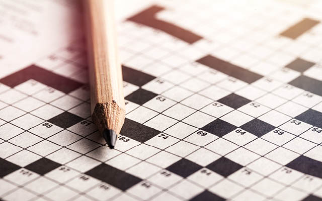 A pencil lies atop a crossword puzzle.