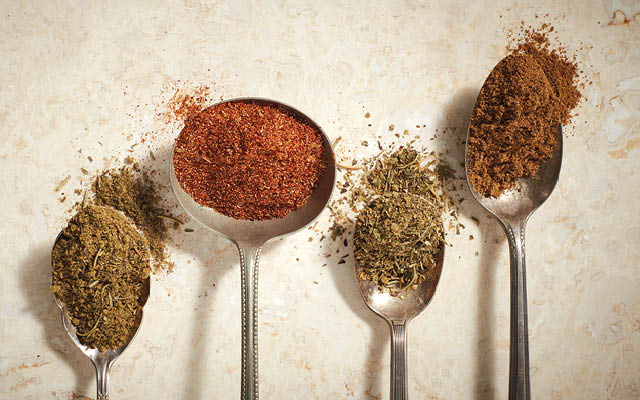 A variety of seasoning blends on spoons.