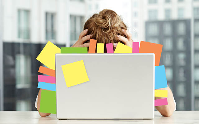 Businesswoman sitting in front of her laptop full of post-it notes
