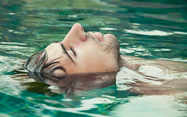 A man is floating in a pool.