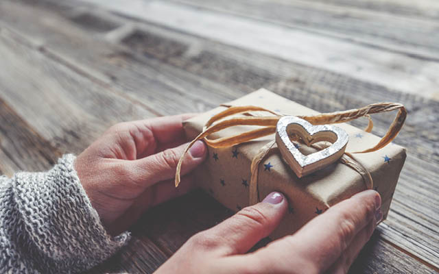 hands holding gift with a heart on it