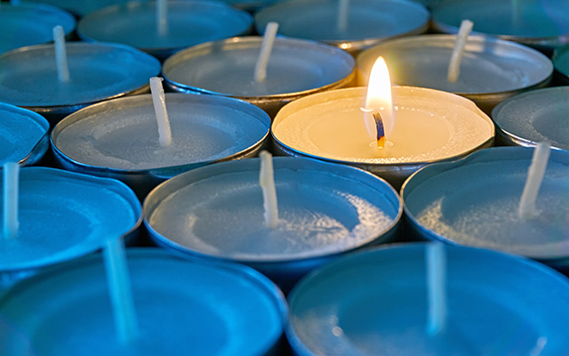 One lone candle is lit among a sea of candles.