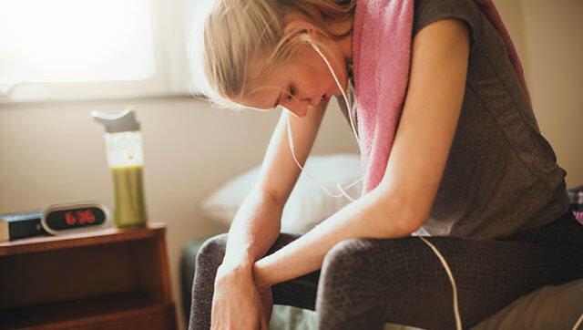 A woman in workout clothes hangs her head.