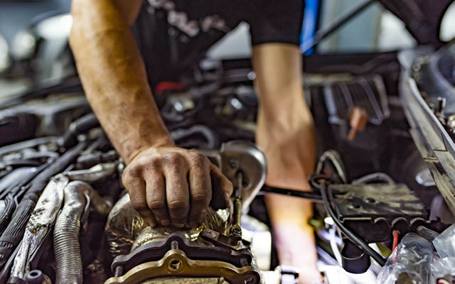 A person works on a car engine.