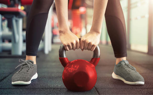 women lifting kettlebell in gym