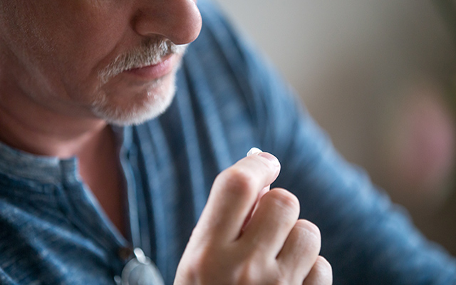 A man holds an aspirin to his mouth.