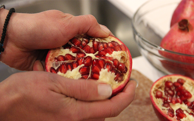 Hands holding half a pomegranate