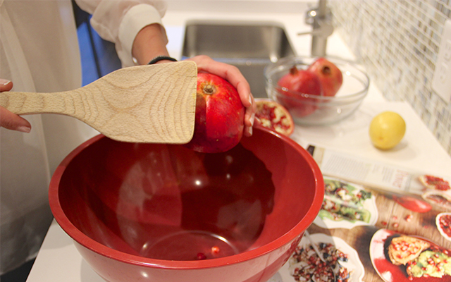 Tapping a pomegranate over a bowl to seed it