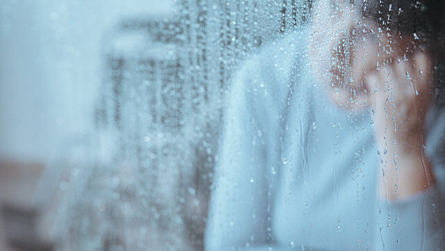 A sad woman looks out the window.