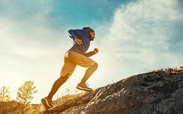 Athlete runs uphill against sunset