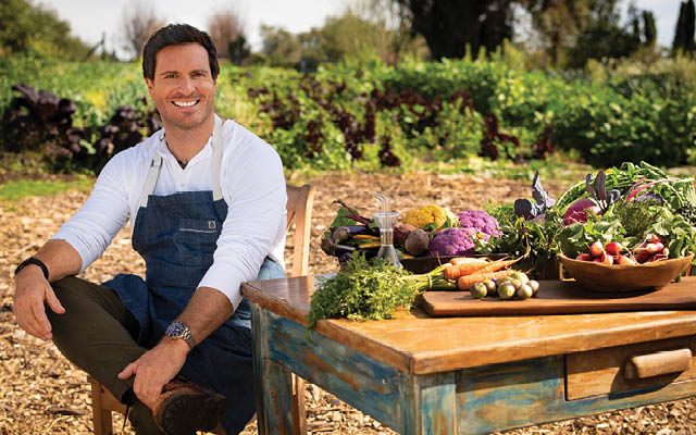 Chef Seamus Mullen smiles next to a table of veggies.