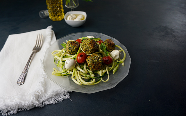 A bowl of zucchini noodles with pesto and tempeh meatballs