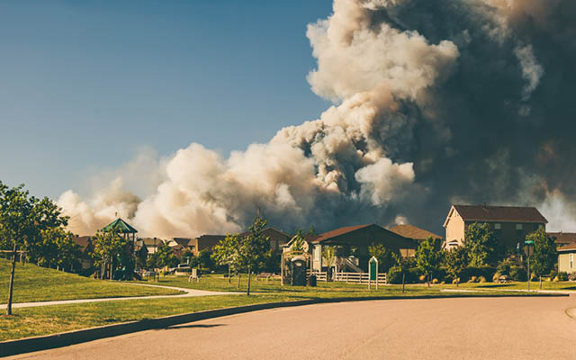 A wildfire burns behind several houses.