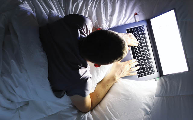 Person on laptop in bed at night