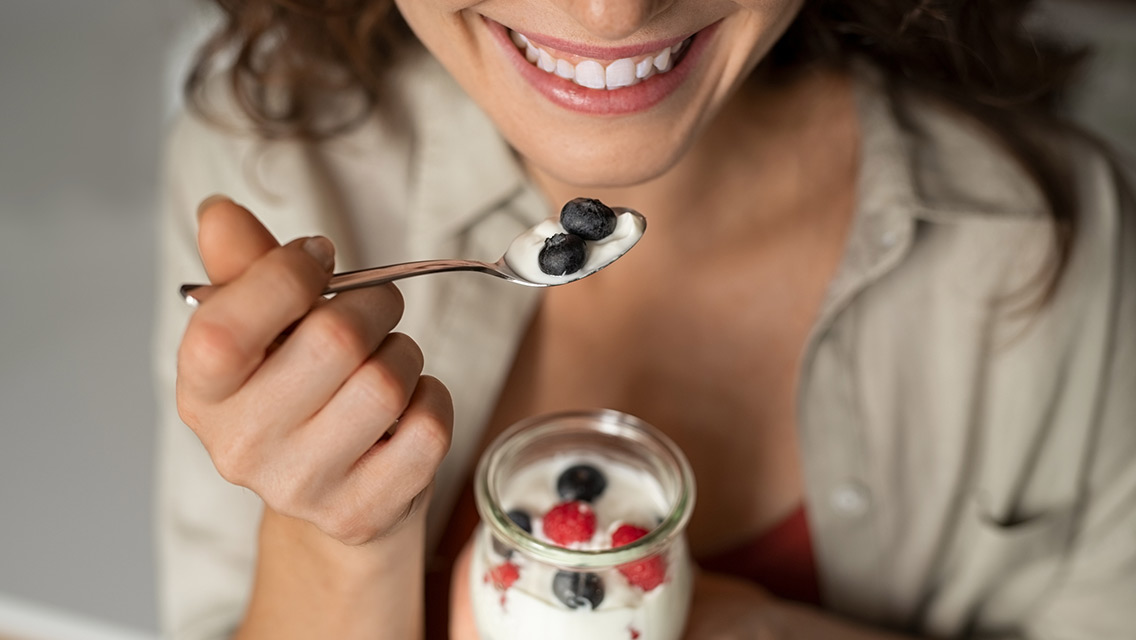 Close up of woman eating berries and yogurt