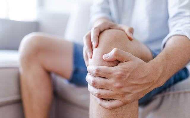 A person holds a knee, as if in pain.