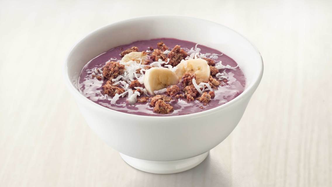 a smoothie bowl topped with banana, granola and shredded coconut