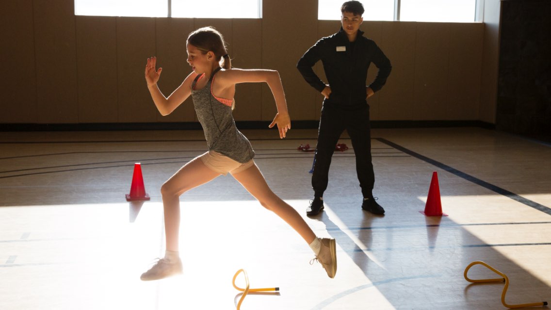 A young girl doing athletic drills in a gym.