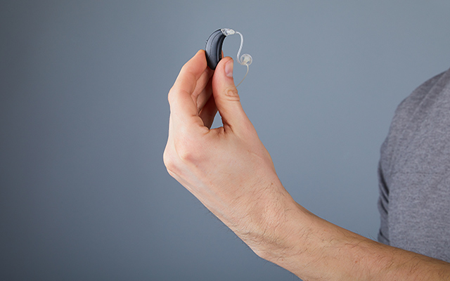 A person holds a hearing aid.
