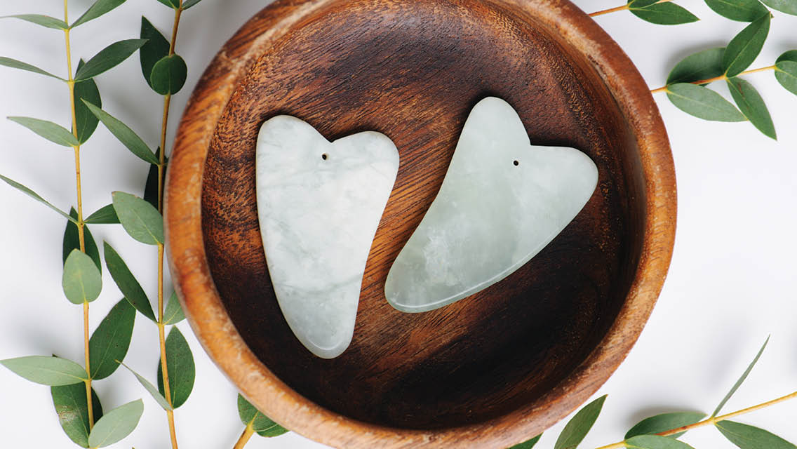 two heart shaped stones sit in a wooden bowl