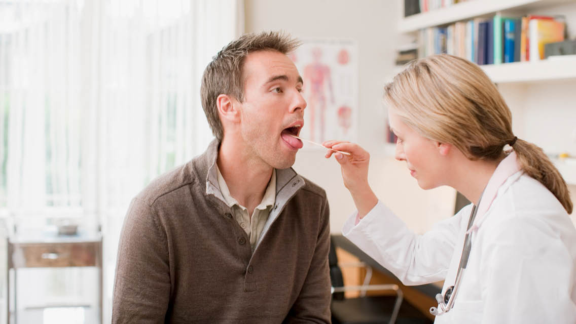 a doctor looks into a man's mouth