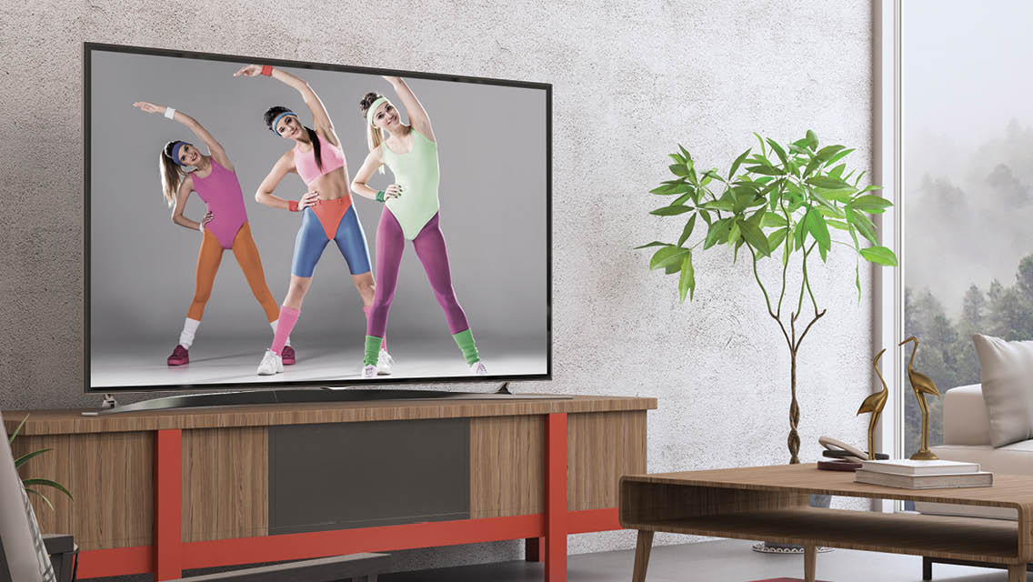 a tv in a living room with three women performing aerobics in neon clothing