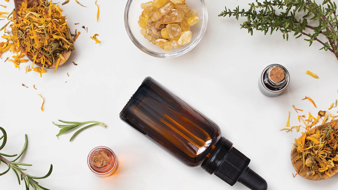 essential oil bottle and various dried herbs and flower