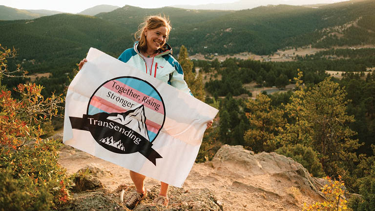 Erin Parisi holds a flag on a cliff's edge